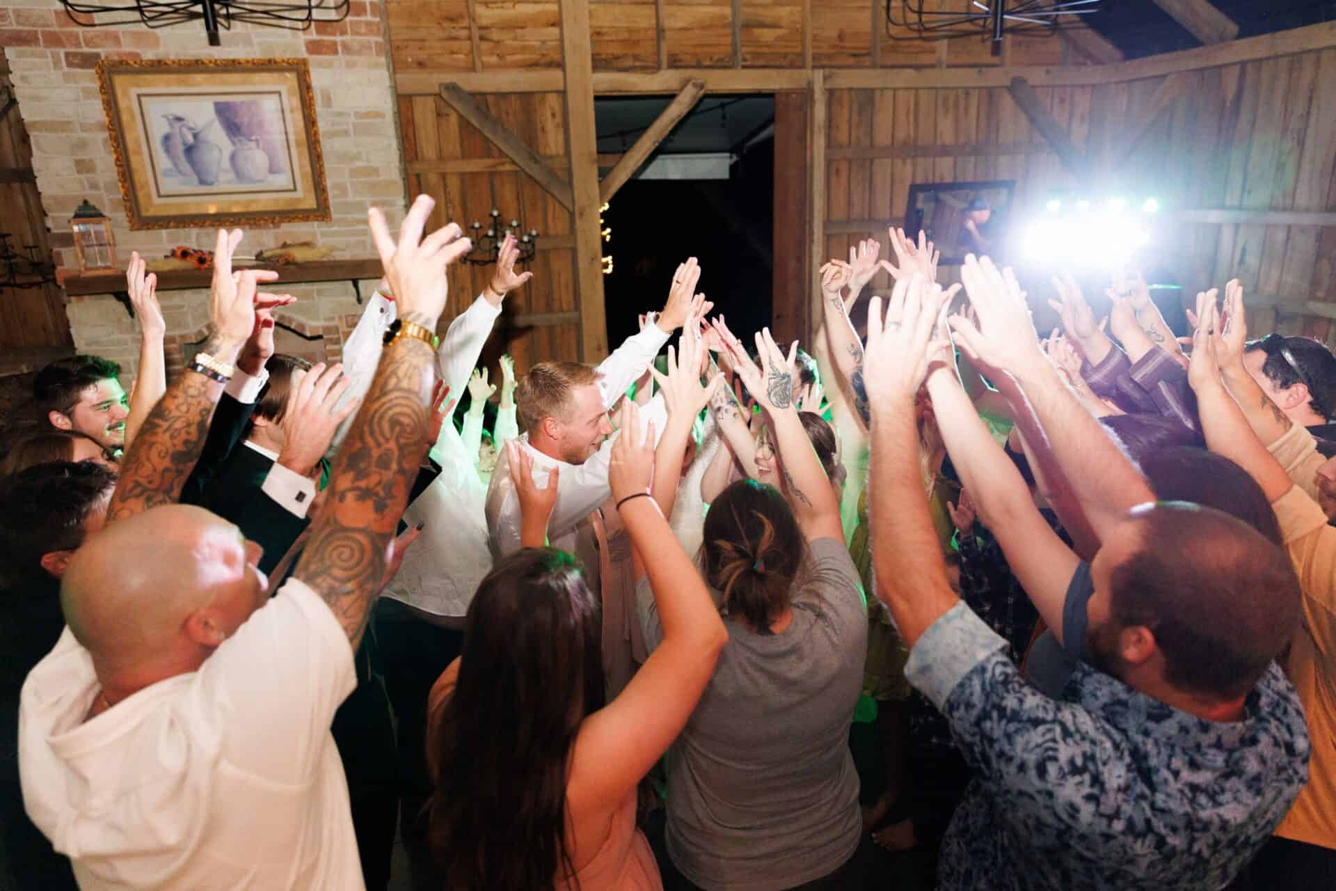 Vibrant wedding celebration at Belle Stone Venue with guests dancing and celebrating in a rustic barn setting.