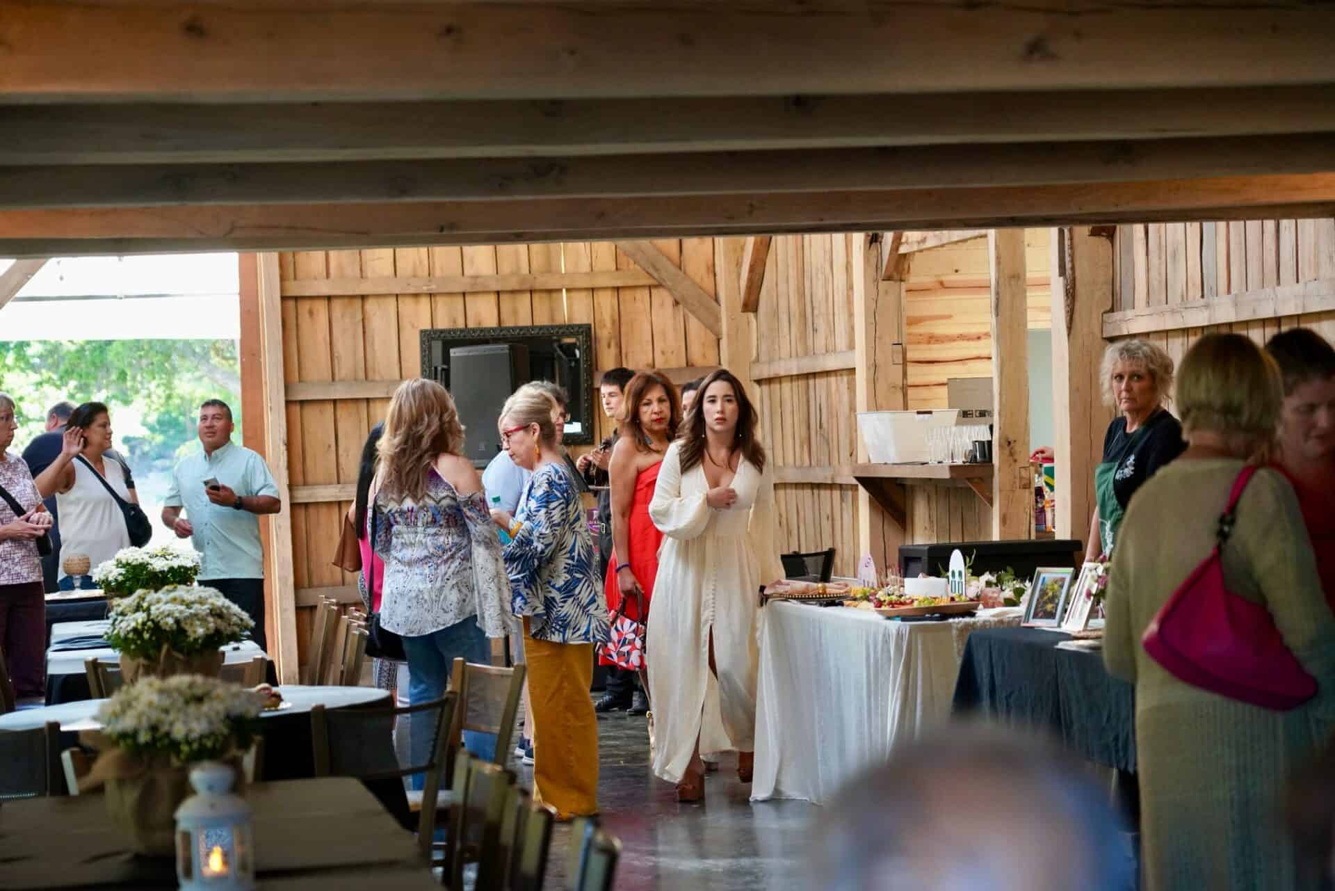 Elegant wooden barn wedding venue with guests mingling and enjoying a celebration at Belle Stone Venue, featuring rustic charm, floral arrangements, and event catering for memorable weddings and special events.