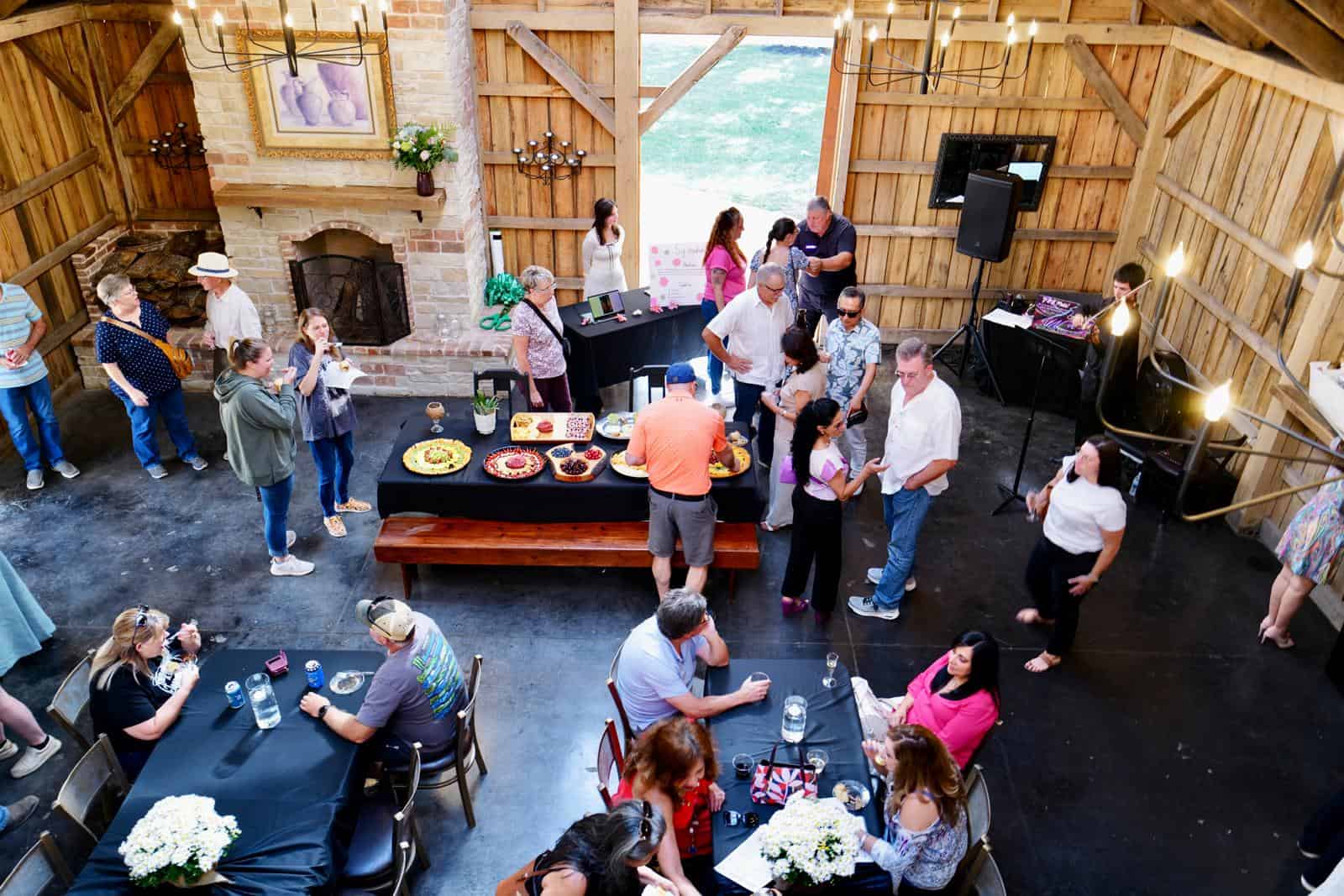 Cocktail reception at Belle Stone Venue with guests enjoying food, drinks, and live music in rustic barn setting featuring wooden walls, fireplace, and elegant decor for weddings and events.