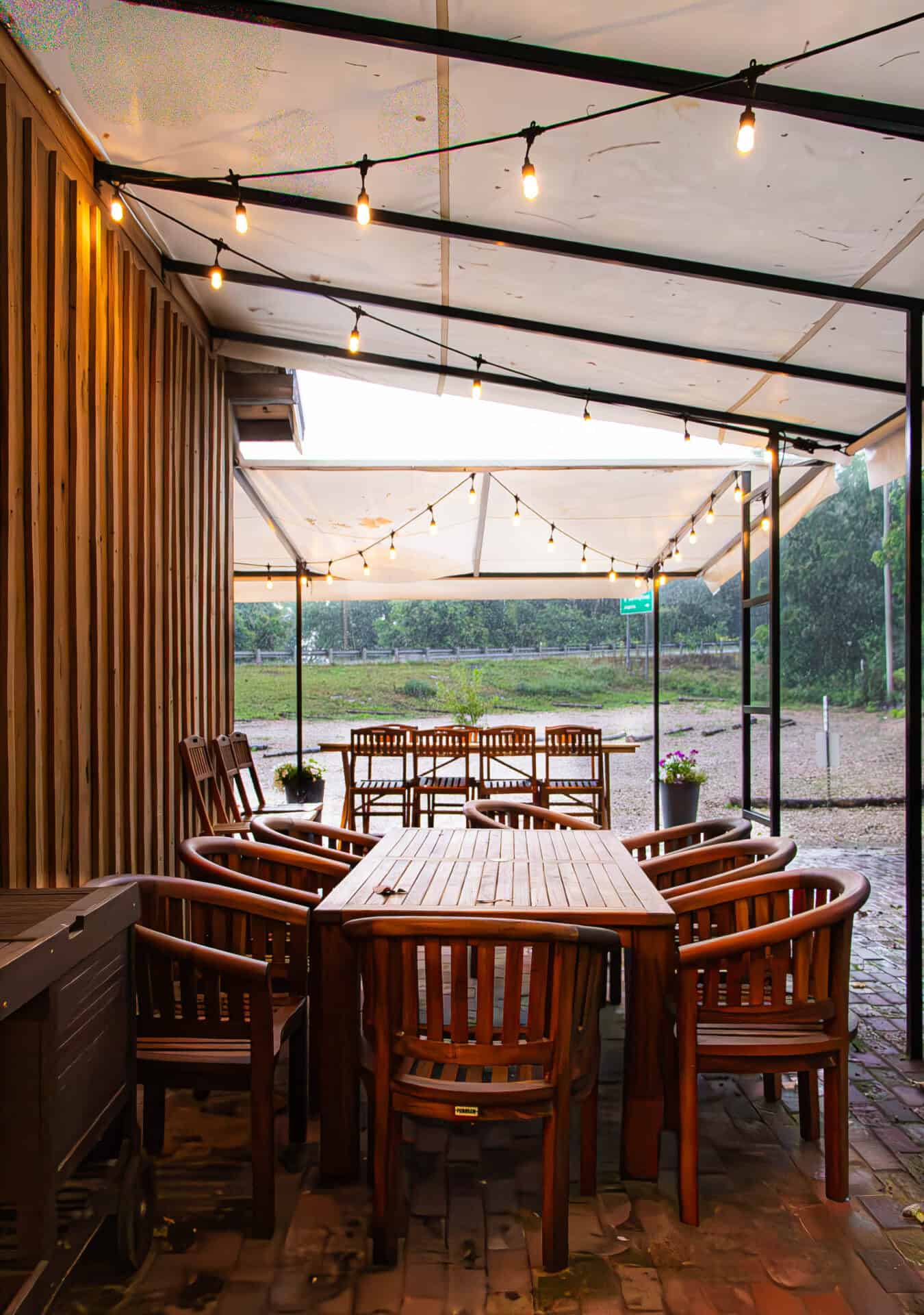 String lights outdoor wedding reception venue at Belle Stone Venue, with wooden tables and chairs under a canopy in a rustic, scenic setting.