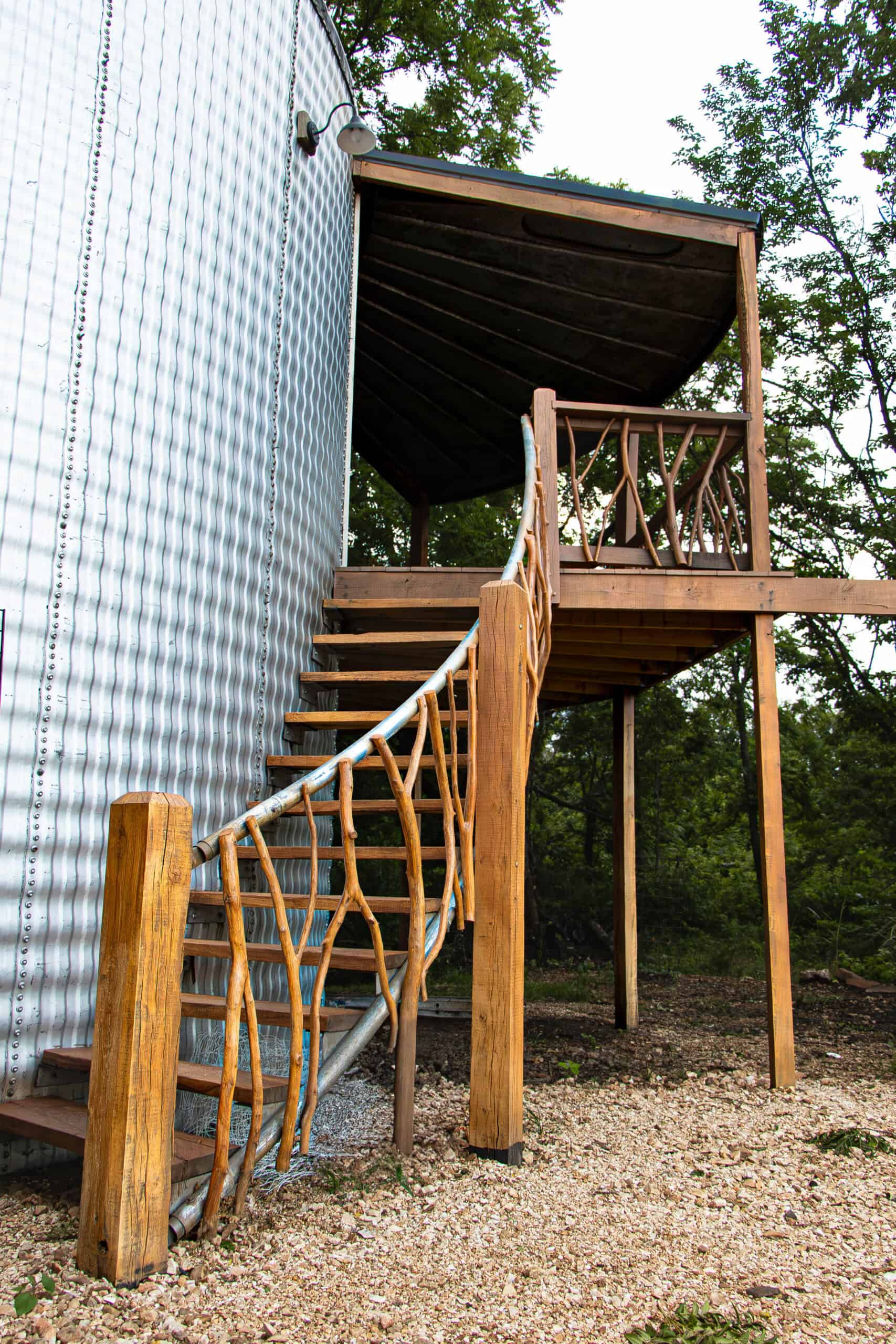 Rustic wooden staircase leading to an outdoor event space at Belle Stone Venue with lush green trees in the background.