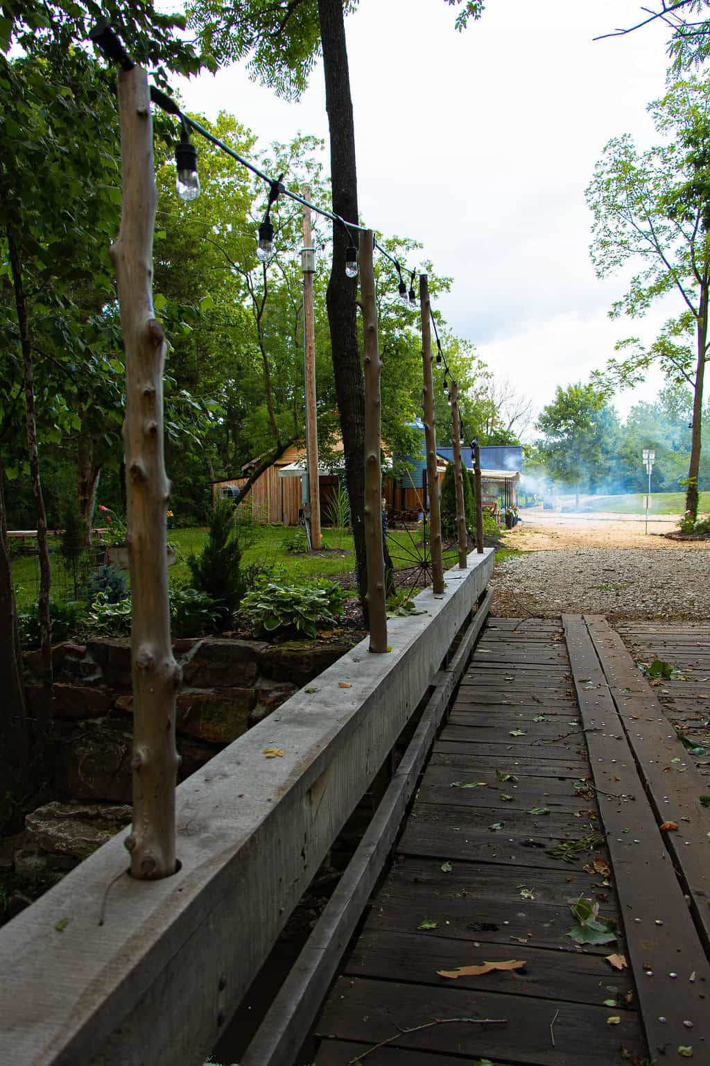 String lights on rustic wooden posts at Belle Stone Venue with outdoor garden and pathway, perfect for wedding and event decor.