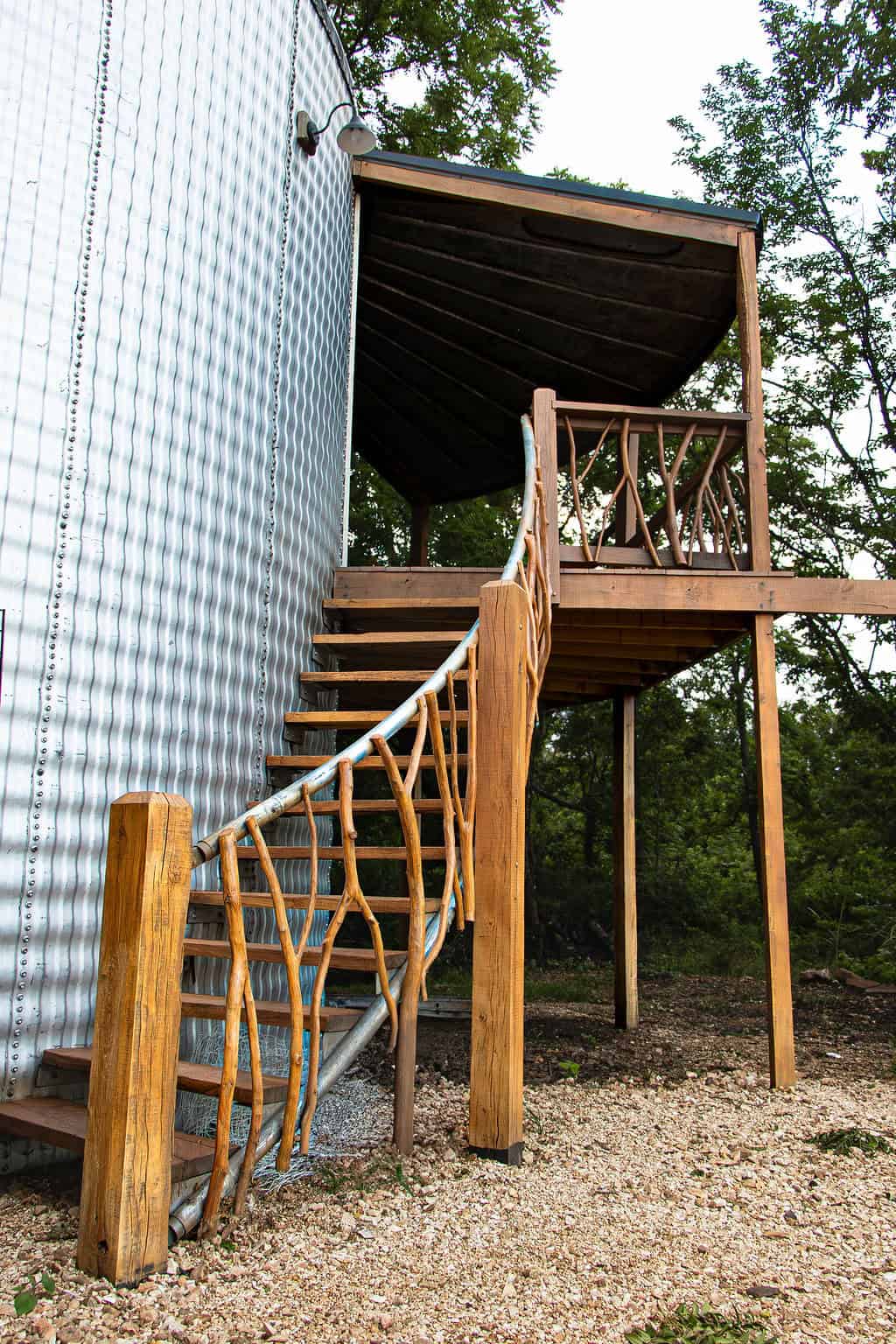 Rustic wooden staircase leading to a cozy balcony at Belle Stone Venue, perfect for outdoor wedding ceremonies and events surrounded by nature.
