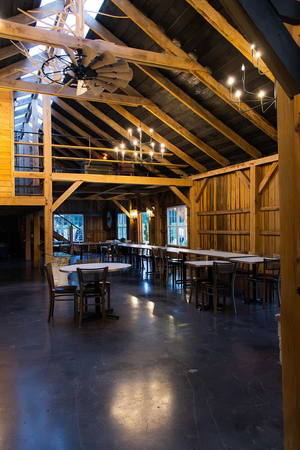 Rustic barn wedding venue with wooden interior, high vaulted ceilings, ambient lighting, and seating arrangements for events at Belle Stone Venue.