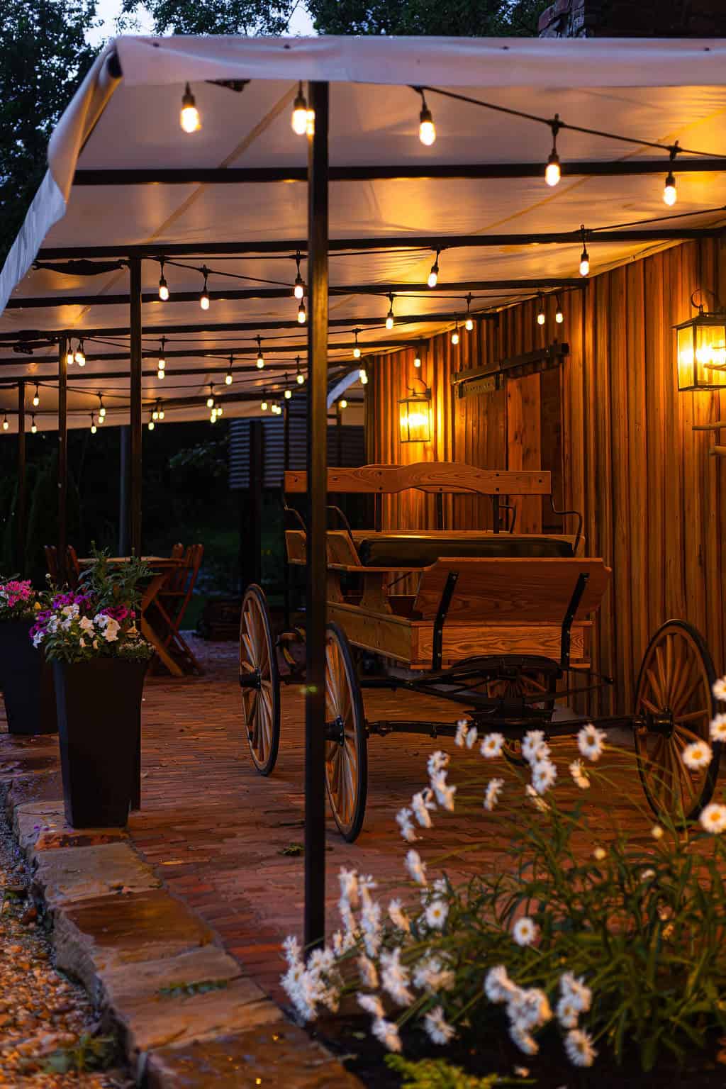 Rustic outdoor event venue with warm string lights, wooden accents, and vintage carriage decor at Belle Stone Venue, perfect for weddings and private celebrations.