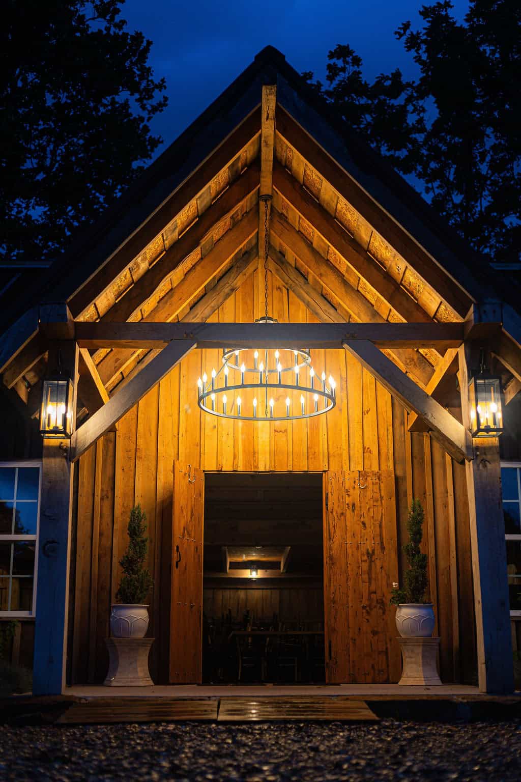 Elegant rustic wooden barn exterior illuminated with warm lighting at night, ideal for weddings and events at Belle Stone Venue.